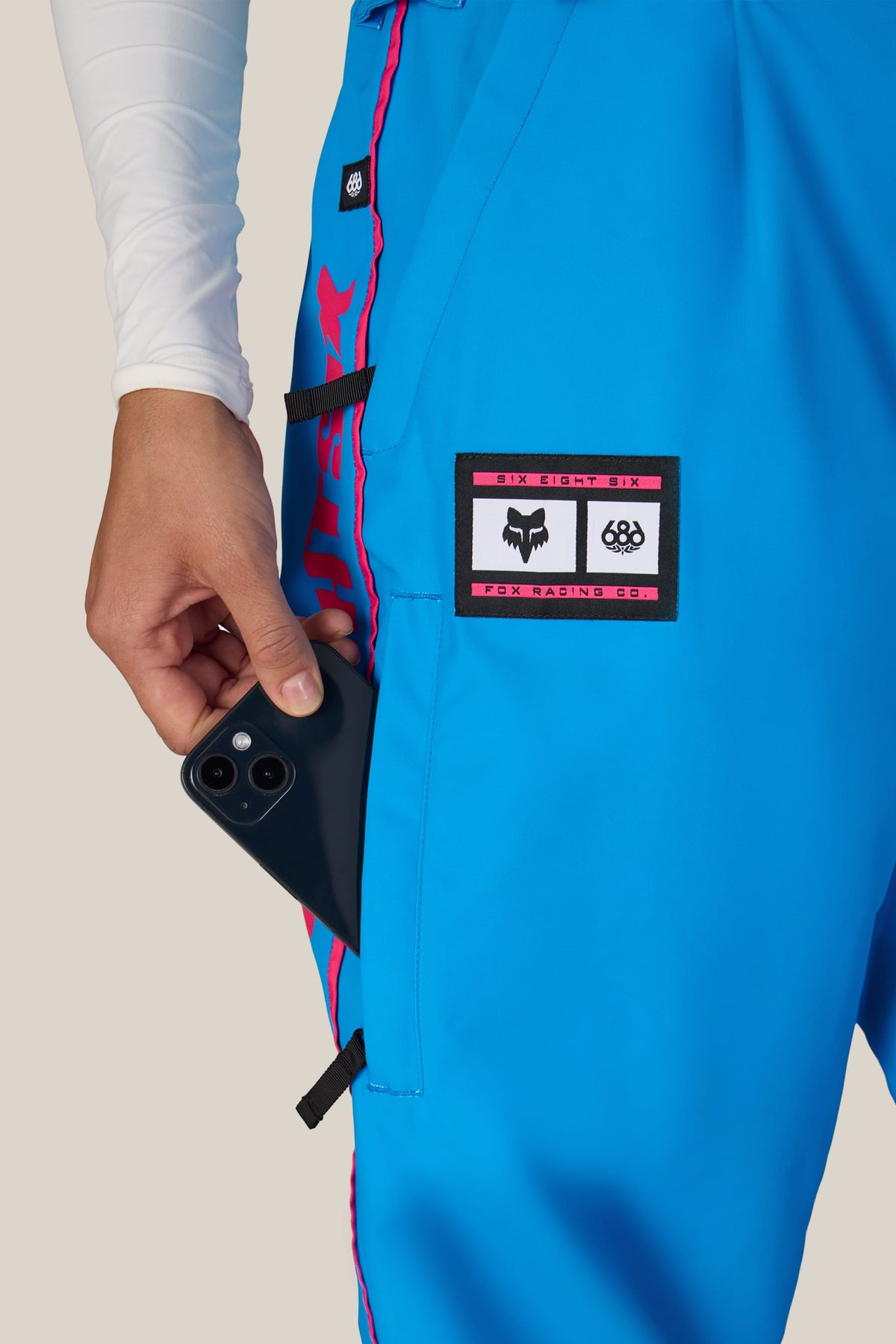 A person wearing blue 686 Women’s Fox Racing 97 Shell Pant with a smartphone in the thigh pocket.
