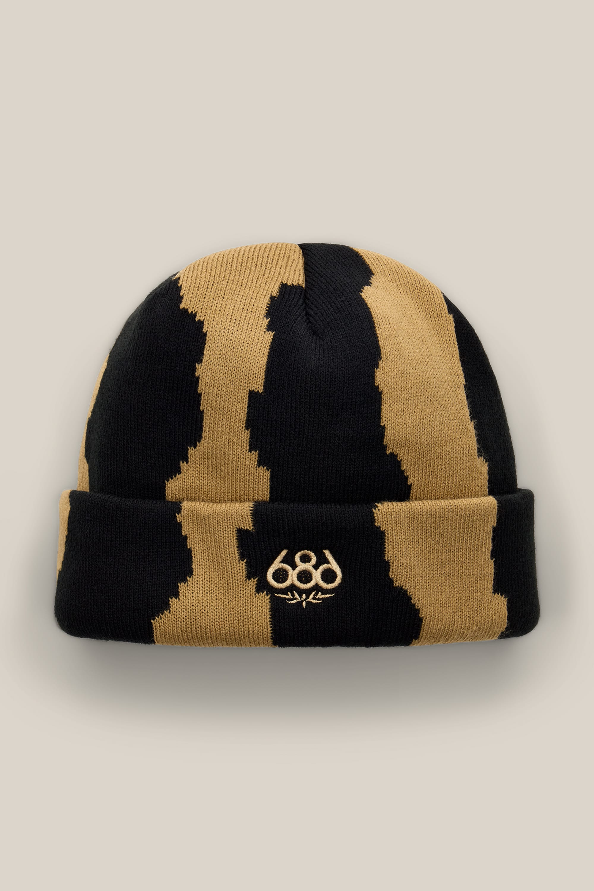 The 686 Torn Beanie by 686 is a black and tan striped acrylic knit beanie, highlighted with a gold-embroidered “686” and signature on the front fold, showcased against a plain beige background.