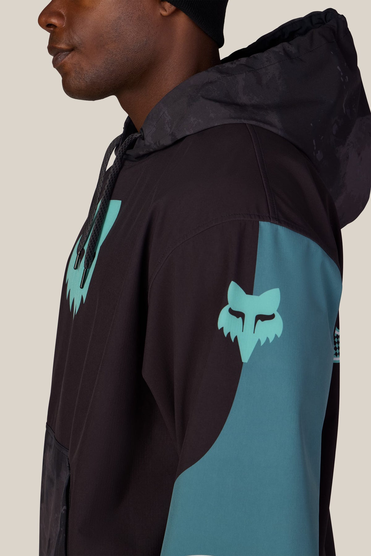 A side profile of a person wearing a 686 Men’s Fox Racing Waterproof Team Hoody, featuring a fox head logo on the sleeve and chest.