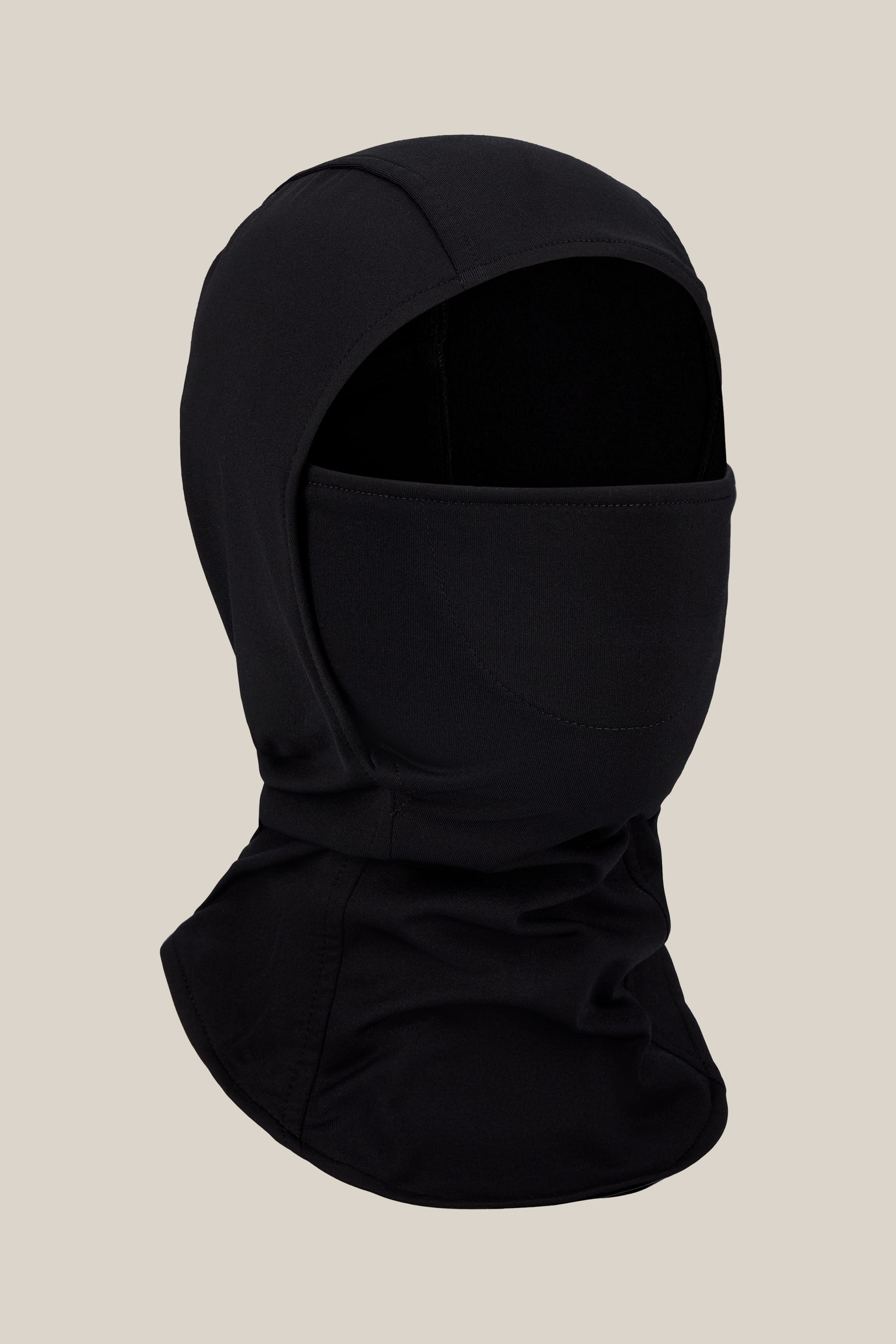 The 686 Hurra Hinged Balaclava by 686 is a unisex black balaclava made from soft merino wool, offering full head and neck coverage with an eye opening, shown against a plain beige background.