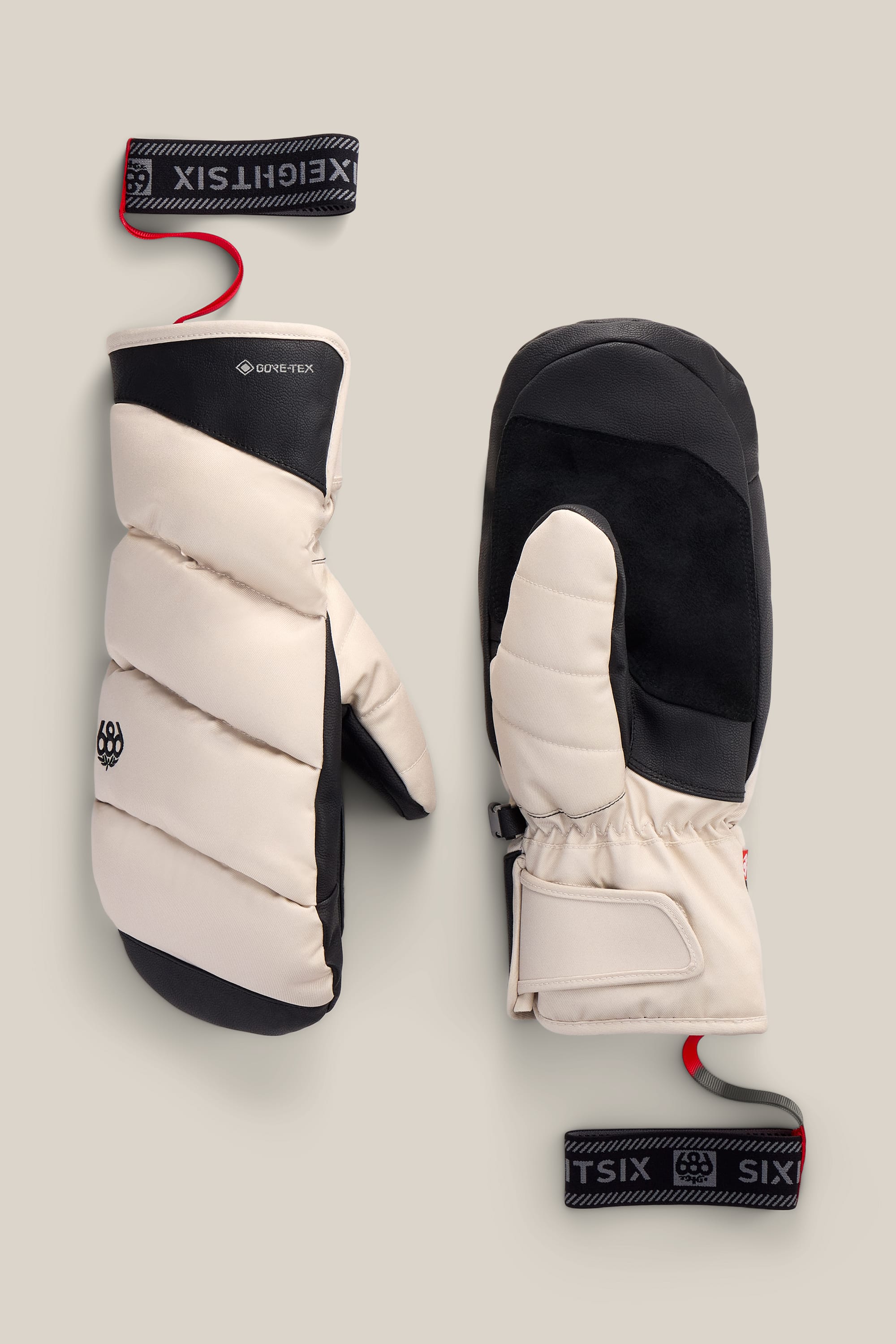 A pair of beige and black 686 Men’s GORE-TEX® Buffer Insulated Mitts featuring detachable wrist straps, displayed on a neutral background. Ideal for men seeking reliable performance in harsh conditions.