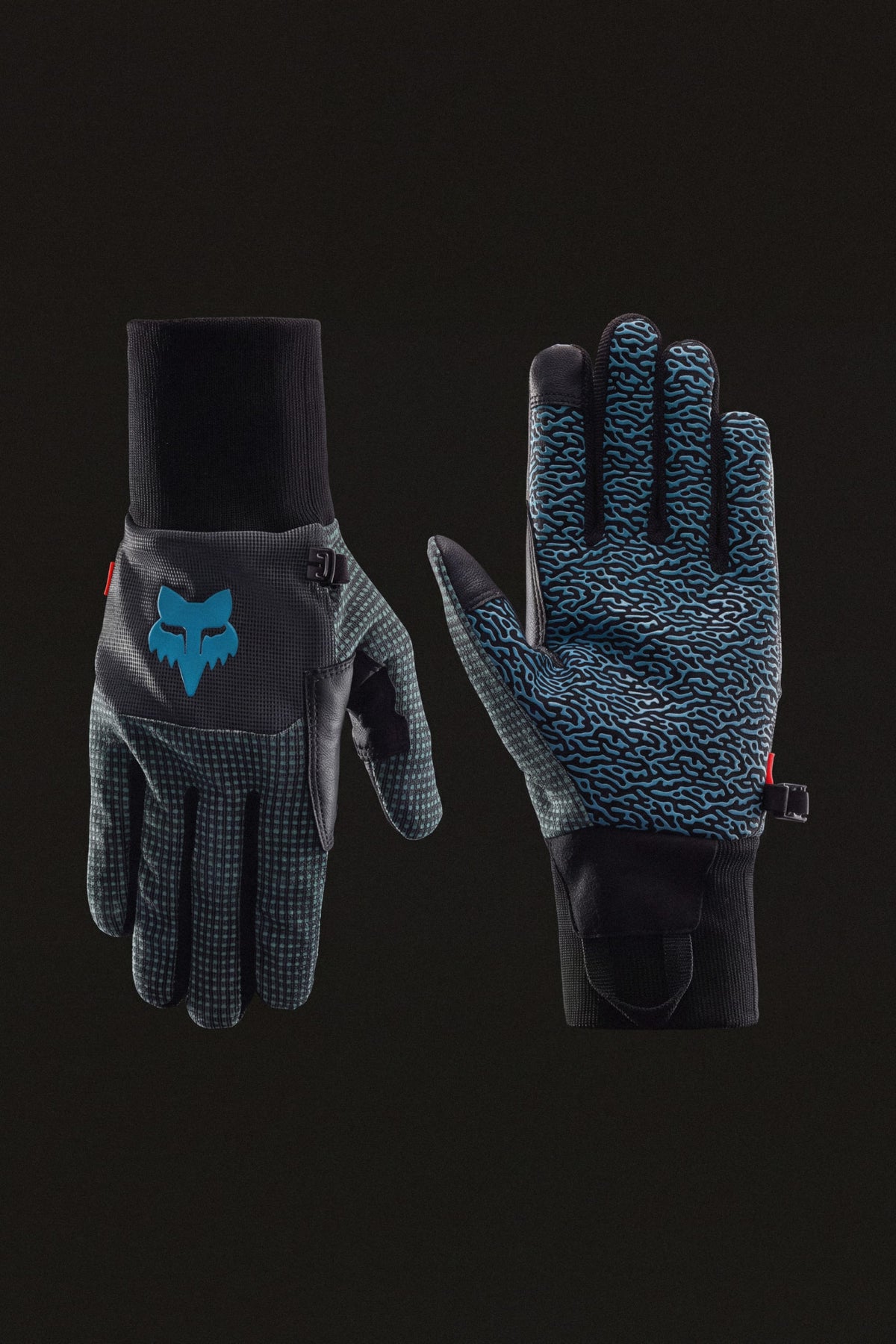 The 686 Men’s Hold Up Pipe Glove features black gloves with blue patterns—one glove has a blue fox logo on the back, and the other has textured gripping on the palm, all set against a black background.