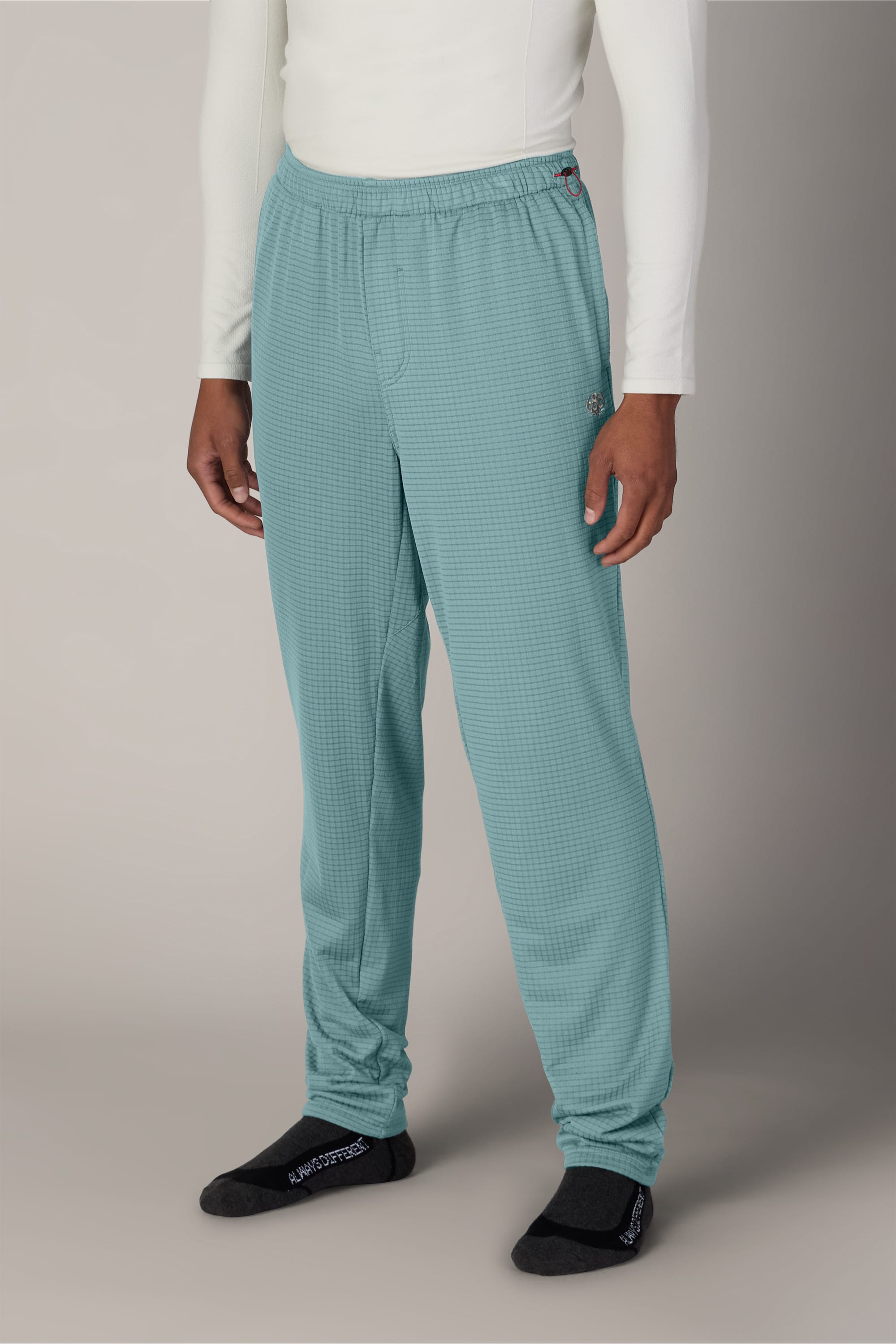 A person is wearing a white long-sleeve shirt, black socks, and 686 Men’s Mission Grid™ Pant by 686—light blue-green checkered men’s knitted pants with an elastic waistband—while standing against a plain background.