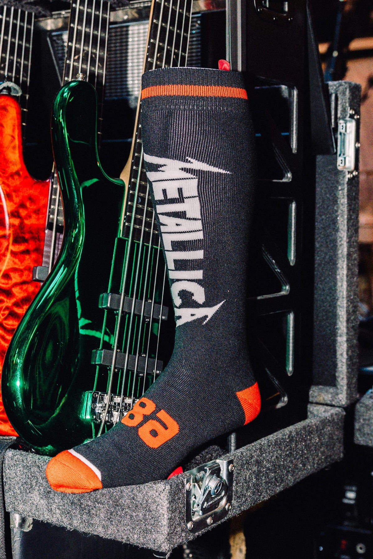 Black acrylic 686 Men’s Metallica Socks featuring the Metallica logo in white, with orange accents on the toe, heel, and cuff.