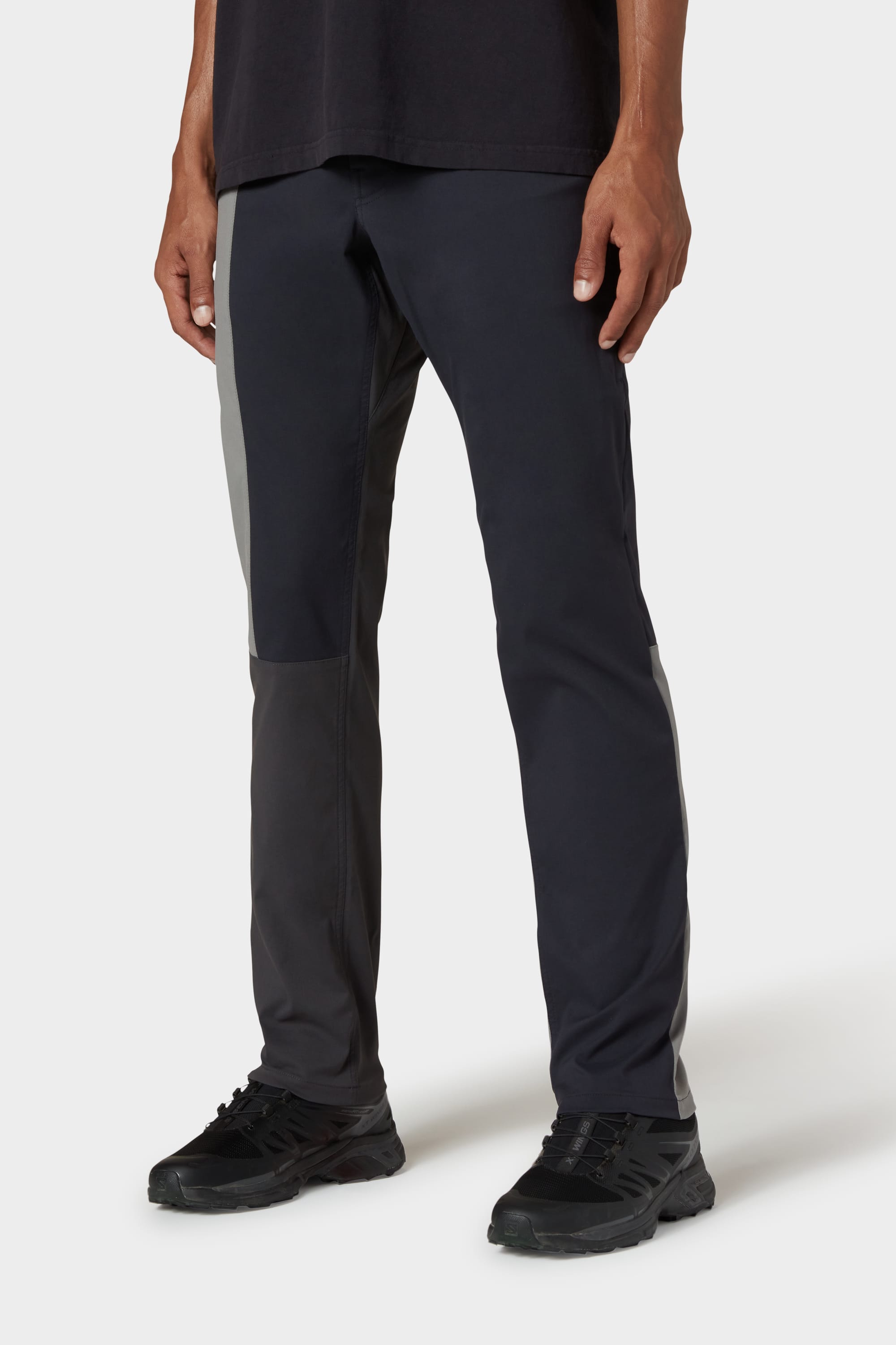 A person models the 686 Men's Everywhere® Reclaimed Pant - Slim Fit in two-tone black and gray deadstock fabric, paired with black athletic shoes, standing against a plain white background. The photo is cropped just below the shoulders.