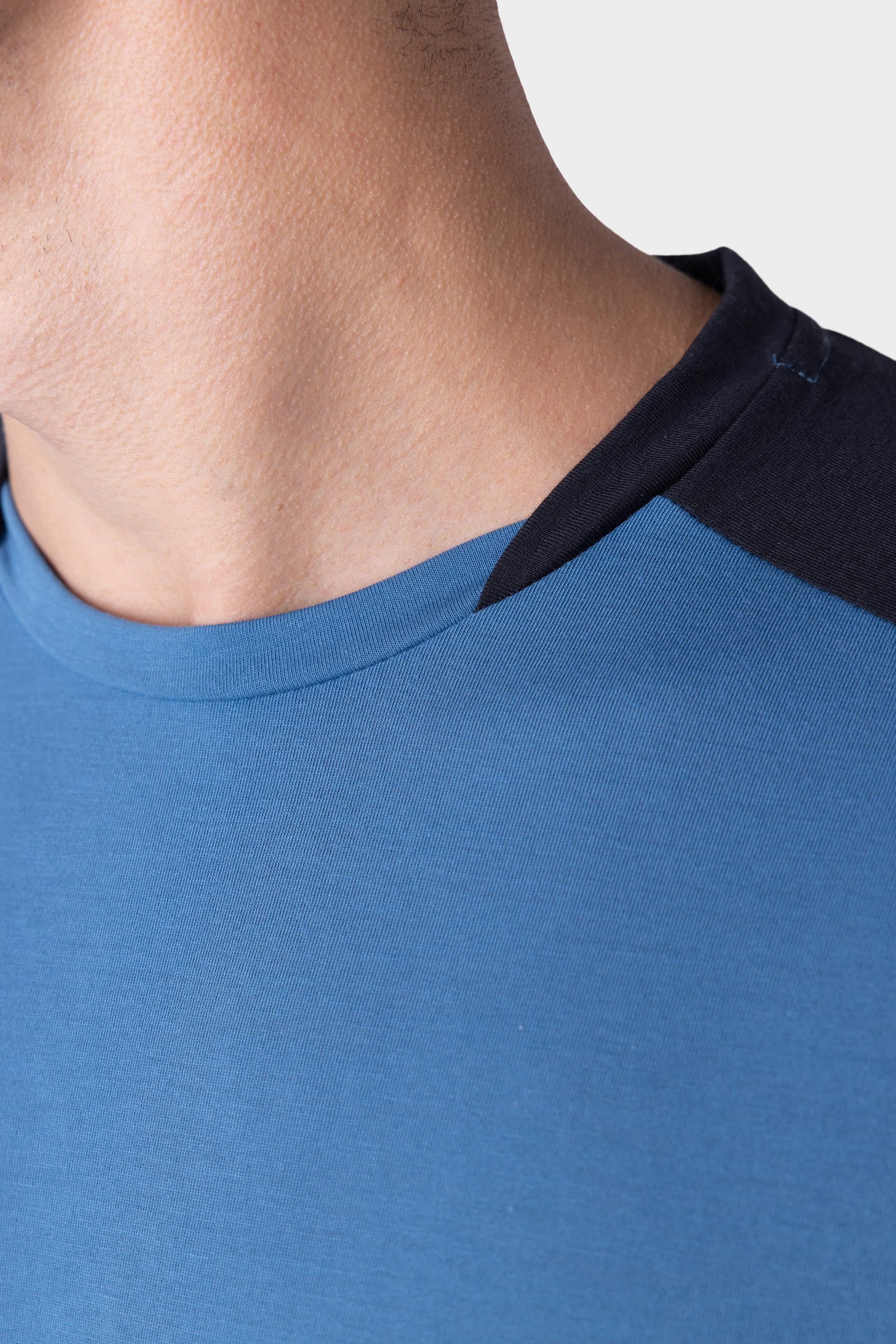 A close-up of a persons neck and shoulder wearing the 686 Mens Rival Short Sleeve Bike Jersey by 686, featuring a blue body with dark navy collar and shoulder detail, shown against a light background.