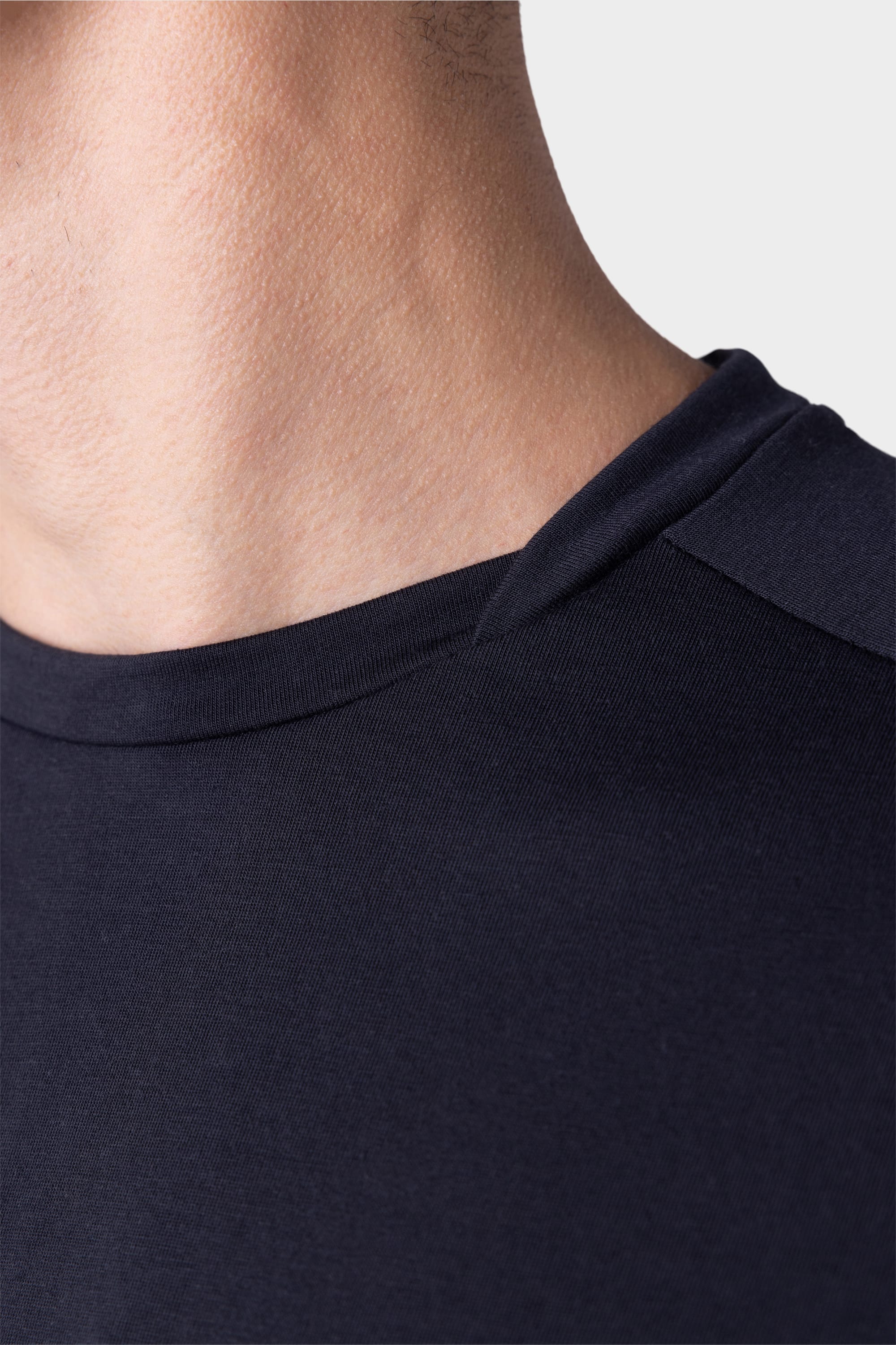 Close-up of a mans neck and shoulder wearing the 686 Mens Rival Short Sleeve Bike Jersey in dark navy blue, by 686, shown against a plain light background.
