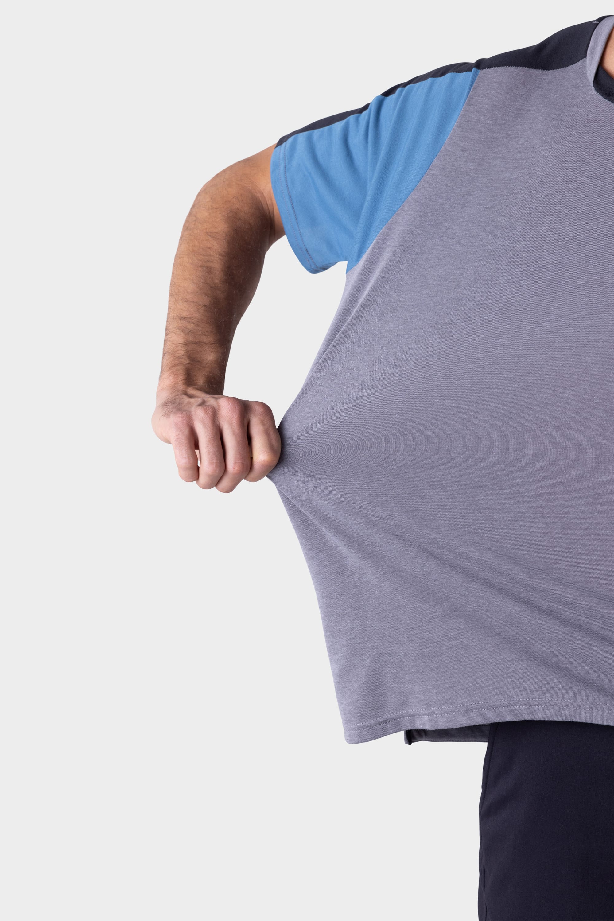 A person wearing the 686 Mens Rival Short Sleeve Bike Jersey stretches the blue and gray shirt outward with their right hand against a white background.