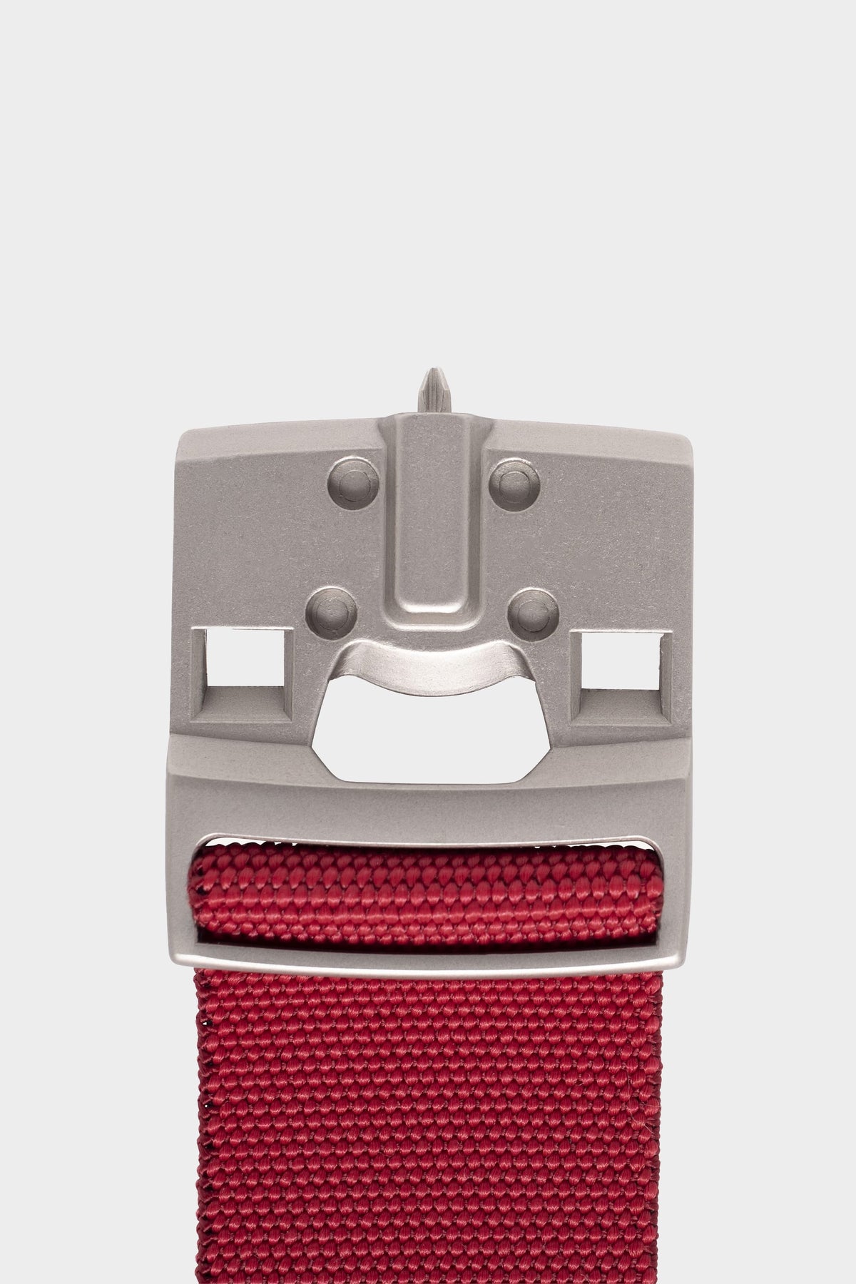 A close-up of the 686 Westwell Clicker Stretch Belt by 686 features a metallic buckle with geometric cutouts shaped like a smiling face, attached to a red belt, set against a plain white background.