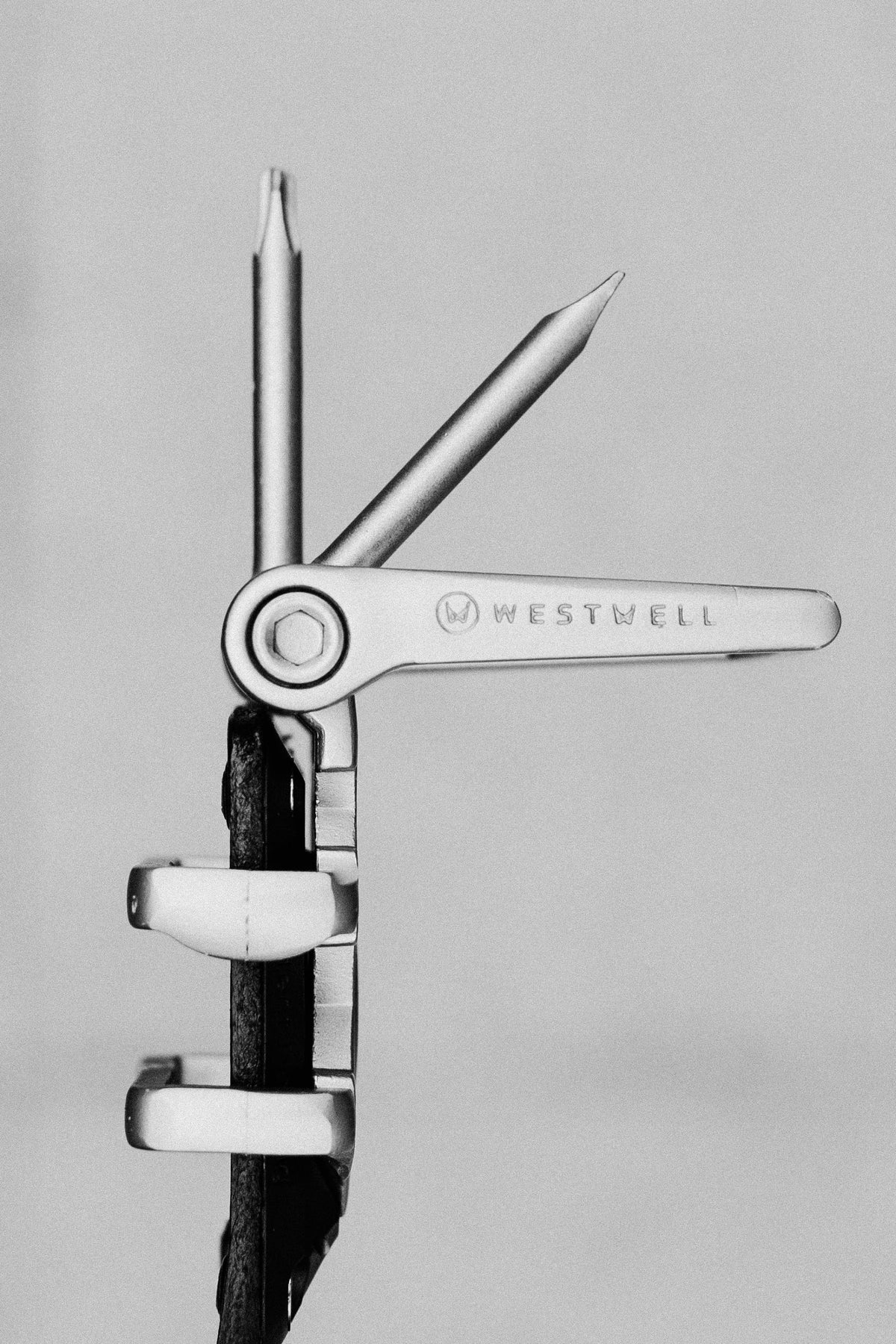A black-and-white photo features the 686 Westwell Voyager Belt engraved with the 686 brand name, showcasing its multitool function with an extended screwdriver and awl against a plain background.