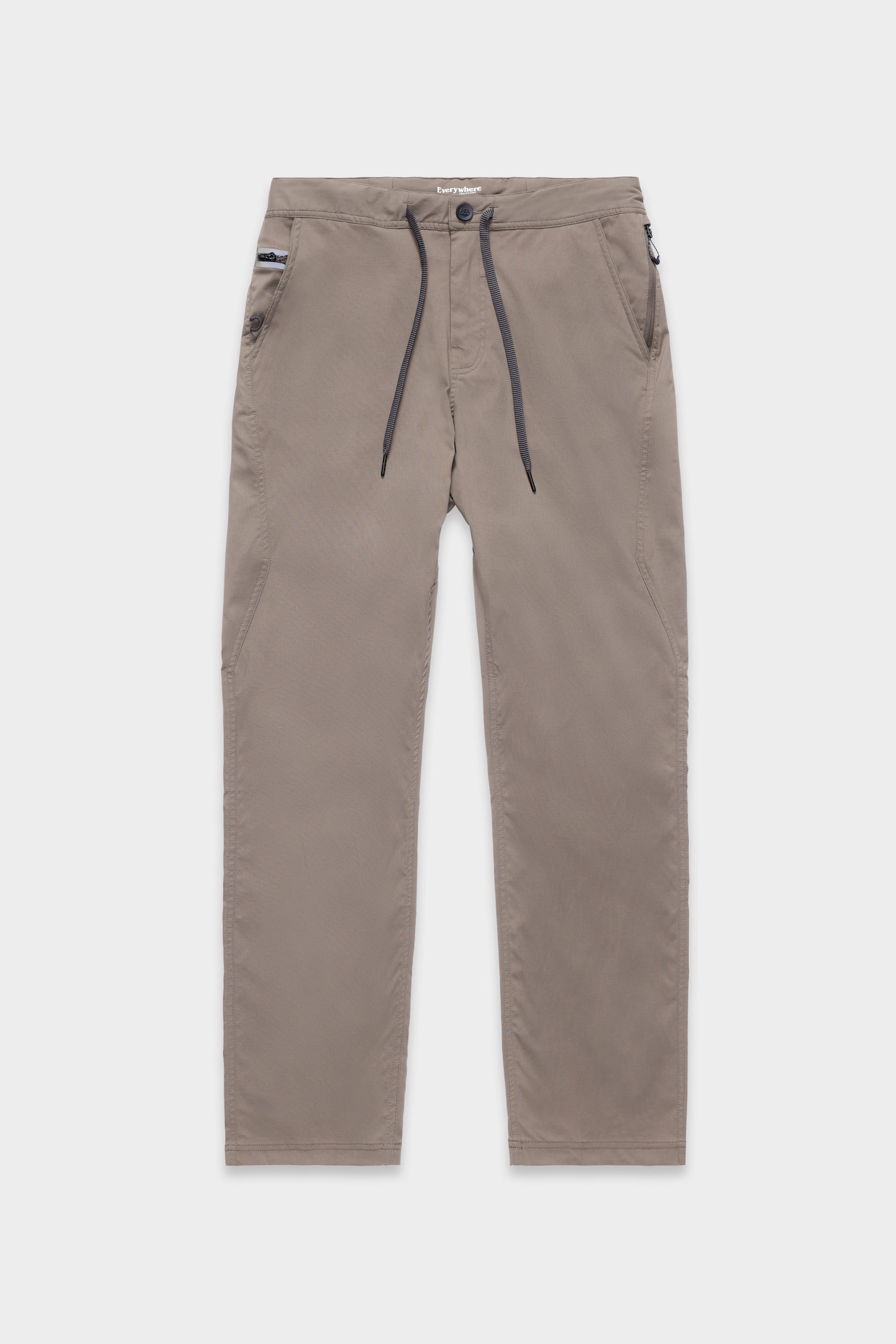 The 686 Mens Platform Bike Pant - Relaxed Fit by 686 features a light brown color, drawstring waist, button and zip fly, two front pockets, and a zippered pocket on the right. Pants are displayed flat on a white background.
