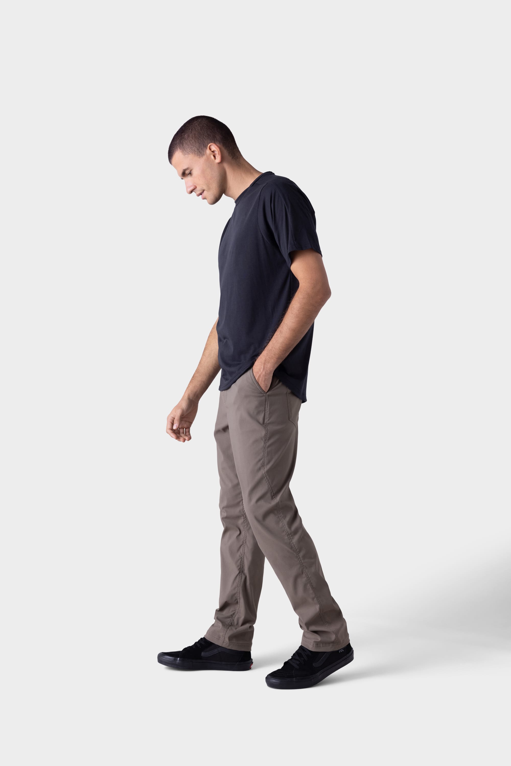 A man wearing the 686 Mens Platform Bike Pant - Relaxed Fit by 686 stands with one hand in his pocket, looking down, against a plain light background.